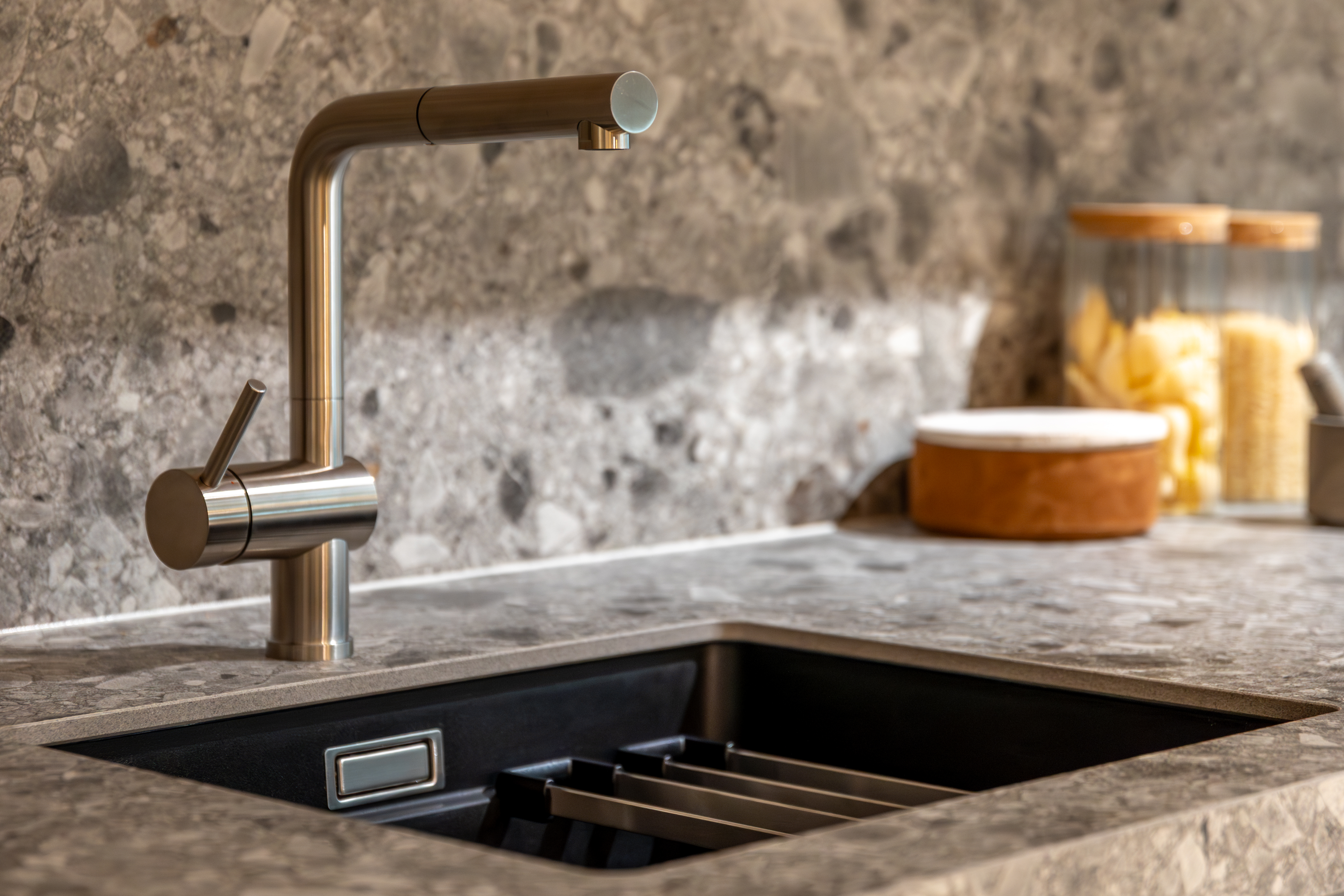 Close-up of a modern kitchen area with an elegant terrazzo countertop, integrated sink, and stylish faucet.