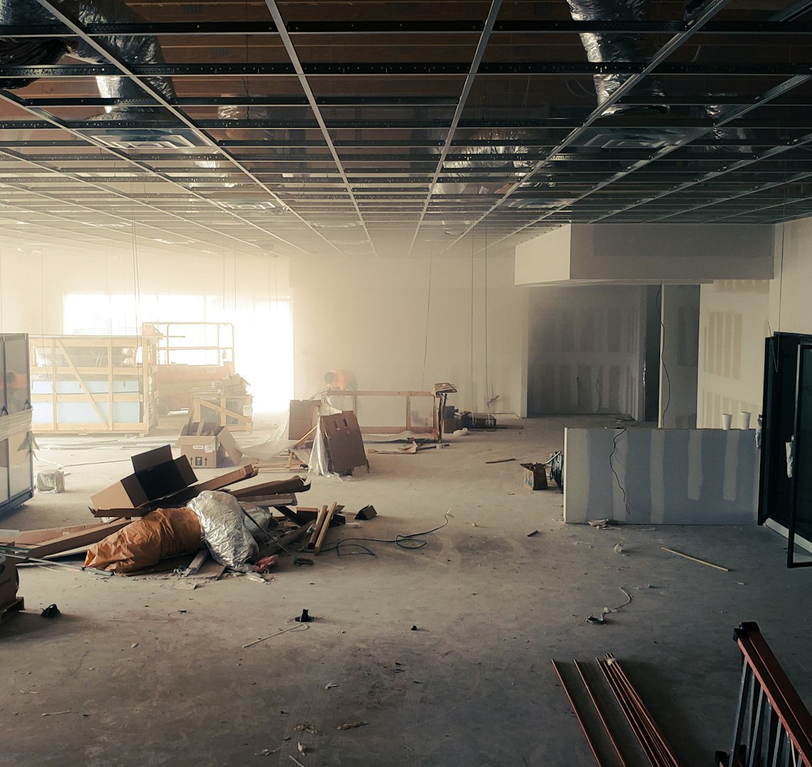 Construction worker installing luxury vinyl plank flooring using glue down method